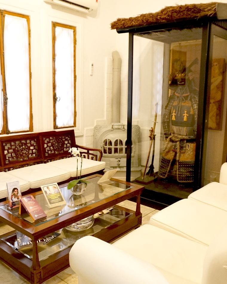Sala de estar da Clincer com sofás claros e armadura samurai em vitrine