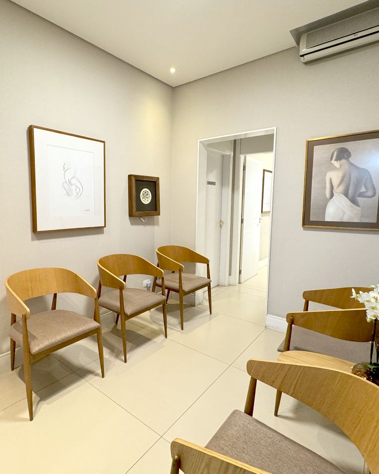 Recepção da Clincer com cadeiras de madeira e quadros