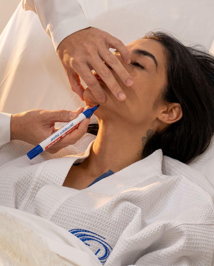 Cirurgião fazendo a marcação no rosto de uma paciente antes do procedimento na Clincer